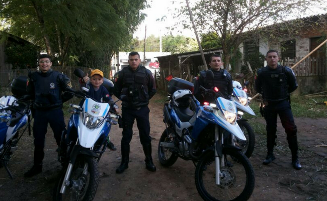 Menino em cima da moto e agentes da Guarda ao lado