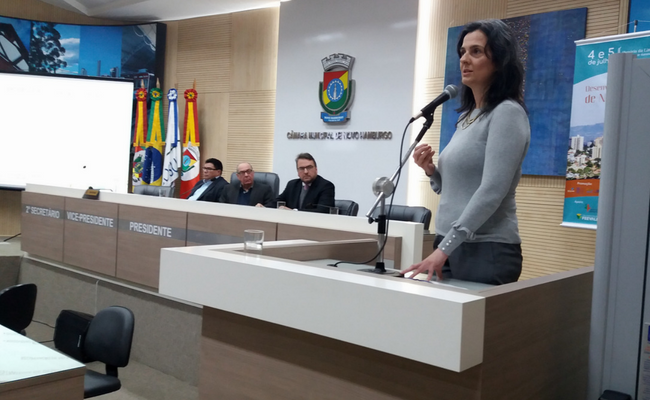 Secretária Paraskevi em pé ao microfone em um pulpito