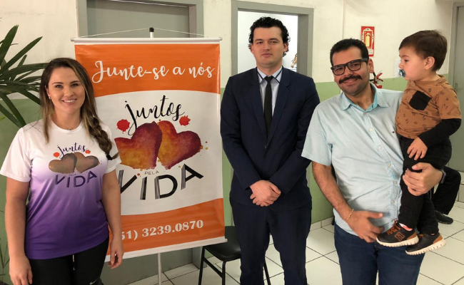 Três pessoas em pé, com um criança no colo 