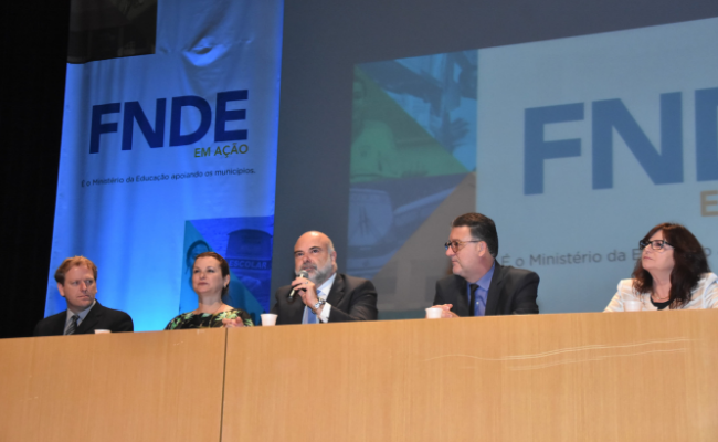 Em um palco, sentados, o presidente da Undime-RS, Marcelo Mallmann, a prefeita de Novo Hamburgo, Fátima Daudt, o presidente substituto do FNDE, Rogério Lot, o reitor da Universidade Feevale, Cléber Prodanov, e a secretária de Educação de Novo Hamburgo, Maristela Guasselli