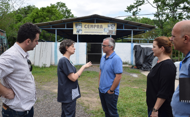 Prefeita à direita em pé. Secretário Udo ao lado. Mais três pessoas em pé. No fundo, o canil municipal