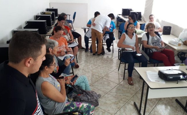 Em uma sala, sentados em cadeiras em formato de l, os alunos do curso
