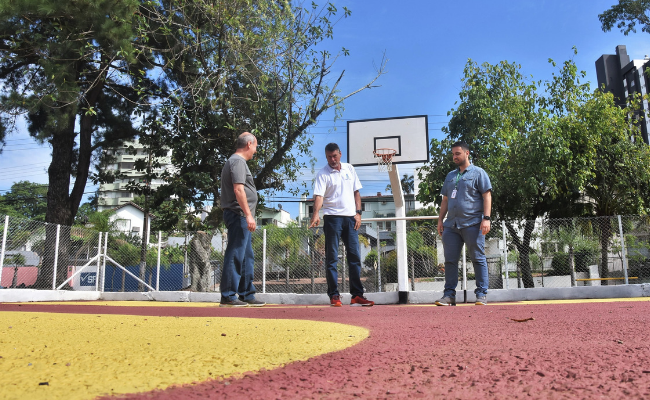 Três homens em pé em uma quadra de basquete
