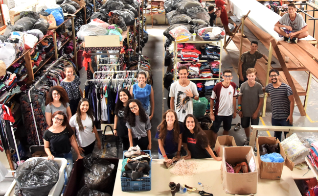 Jovens em pé com muitas roupas ao redor