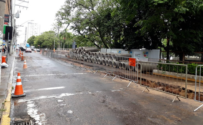 Rua de asfalto com canos empilhados no lado direito