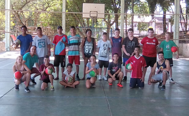 Em uma quadra, jovens paradas em pé e agachados para a foto