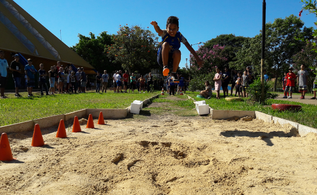 Menino pulando em uma caixa de areia