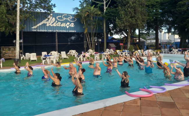 Em uma piscina, mulheres fazem exercícios uma ao lado da outra