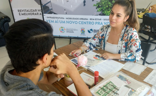 Um jovem e uma jovem sentados cada um de um lado de uma mesa
