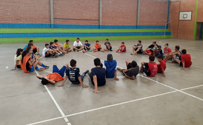 grupo de jovens sentados em círculo em uma quadra