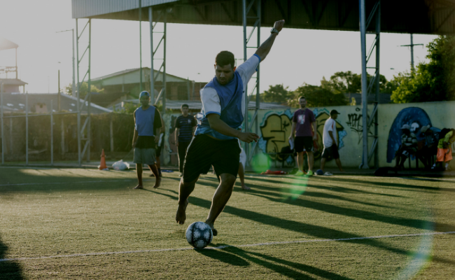 Menino chutando uma bola na marca do pênalti 