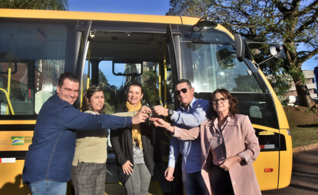Com um ônibus ao fundo, a prefeita e a secretaria de educação mais três pessoas seguram a chave do ônibus