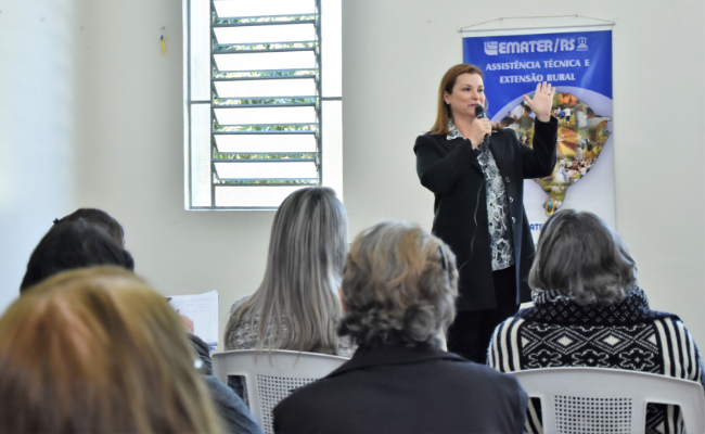 Prefeita Fátima ao microfone e grupo de mulheres sentadas a sua frente