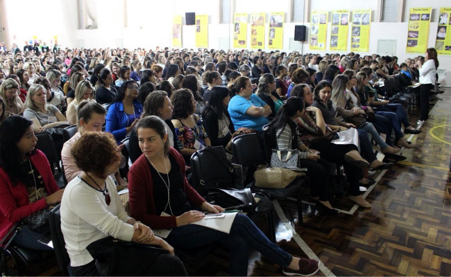 Grande público sentado em cadeiras lado a lado