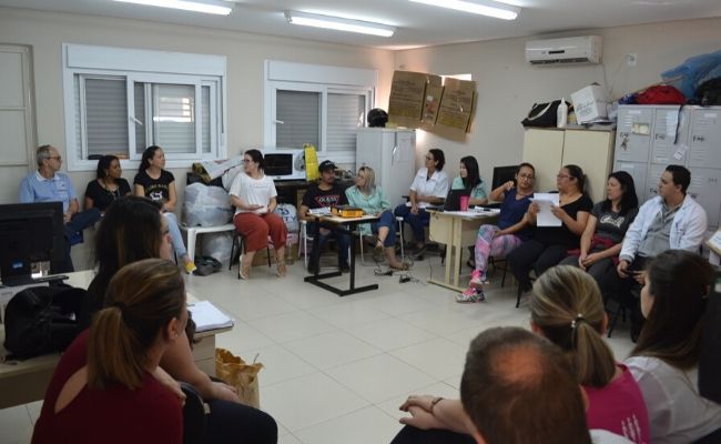 Em uma sala, pessoas sentadas em círculo